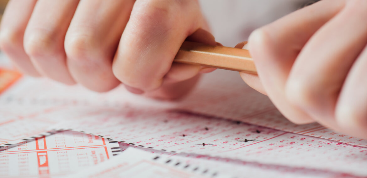 cropped view of upset gambler braking pencil near lottery tickets