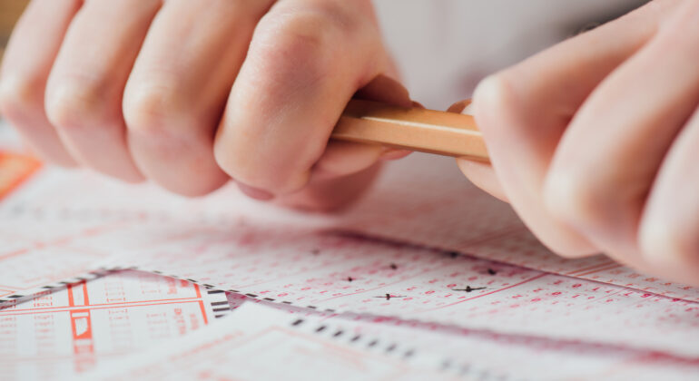 cropped view of upset gambler braking pencil near lottery tickets